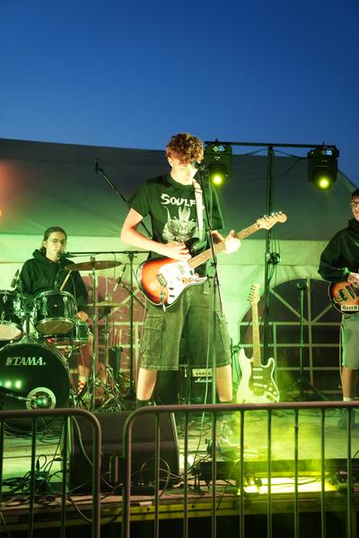 Band on stage under green lights with smoke